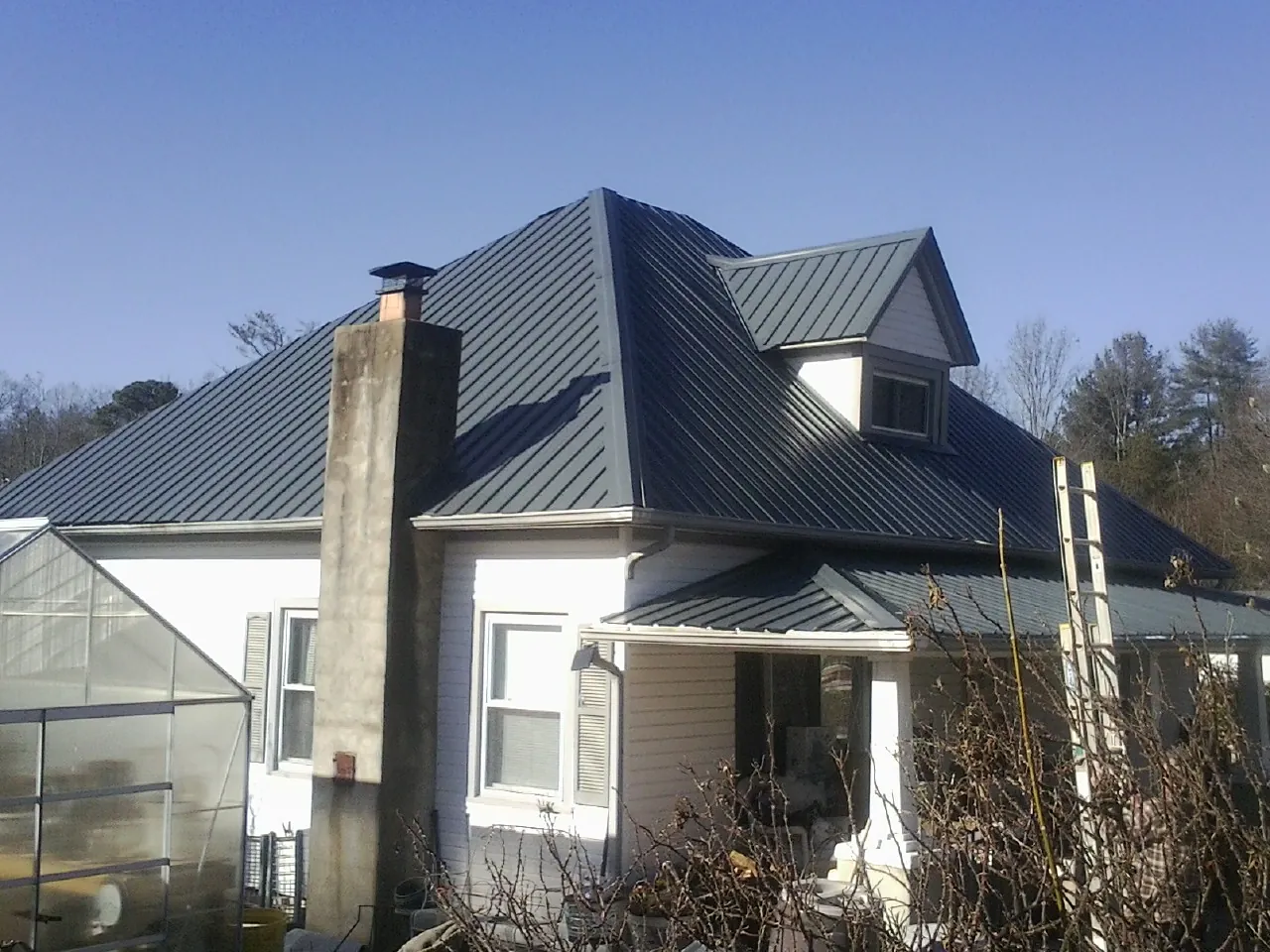 Dark blue standing seam metal roof on a white farmhouse with dormer — Slate & Tile Roof Repair by Roofing Brothers in West Blocton