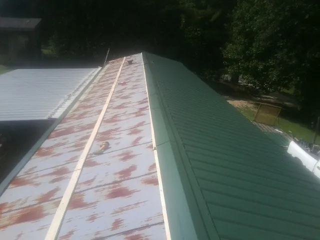 Old rusted panels beside newly installed green metal roofing — Wind Damage Roof Repair by Roofing Brothers in West Blocton