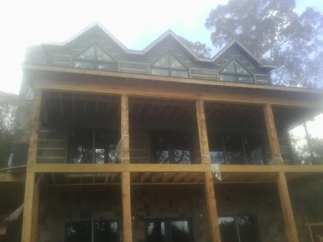 Dormers and porch framing on a large log home under construction — Roof Coating work by our crew in West Blocton