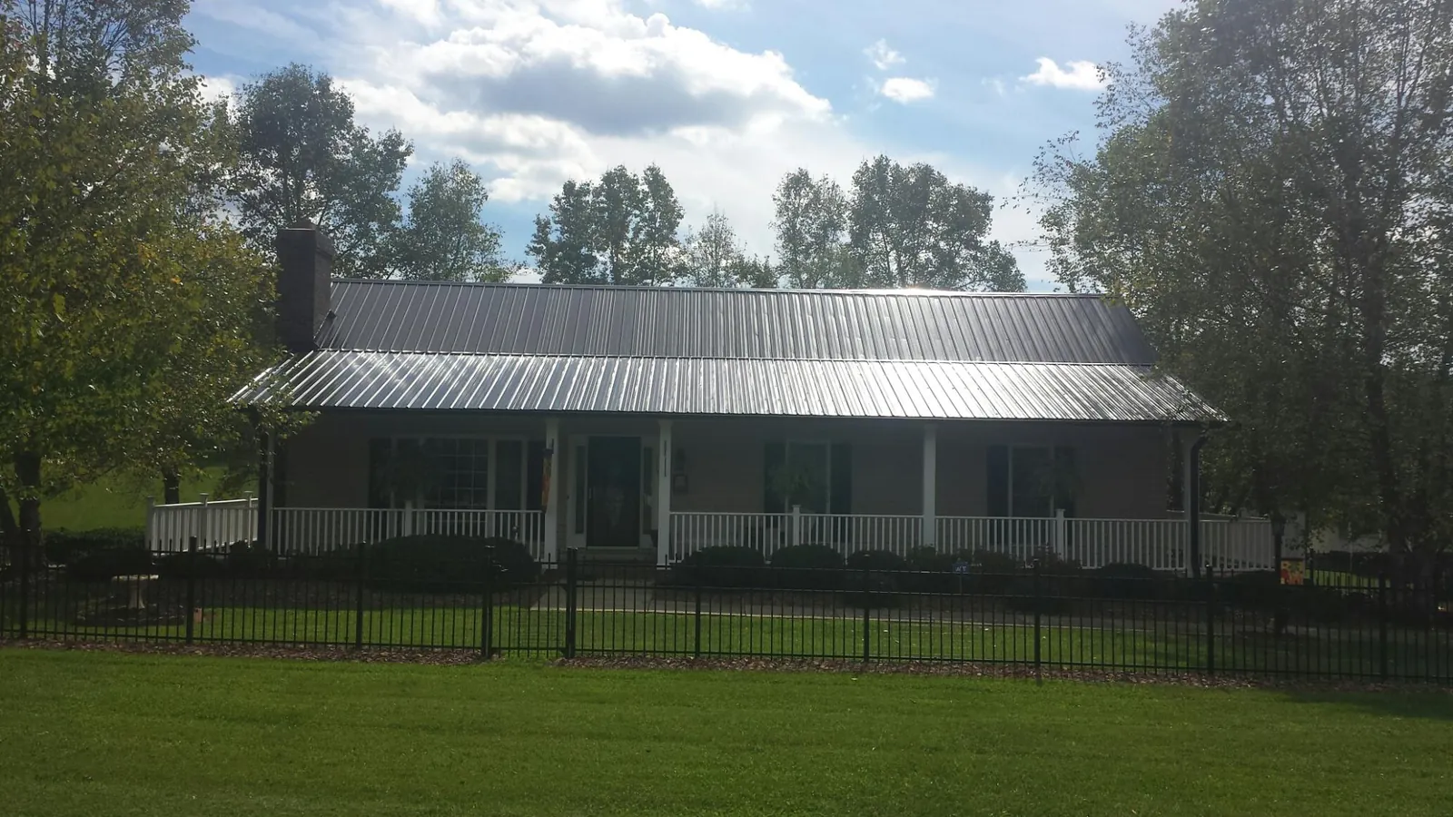Gray metal roof on a brick ranch with a full width front porch — Gutter Guard Installation work by our crew in West Blocton