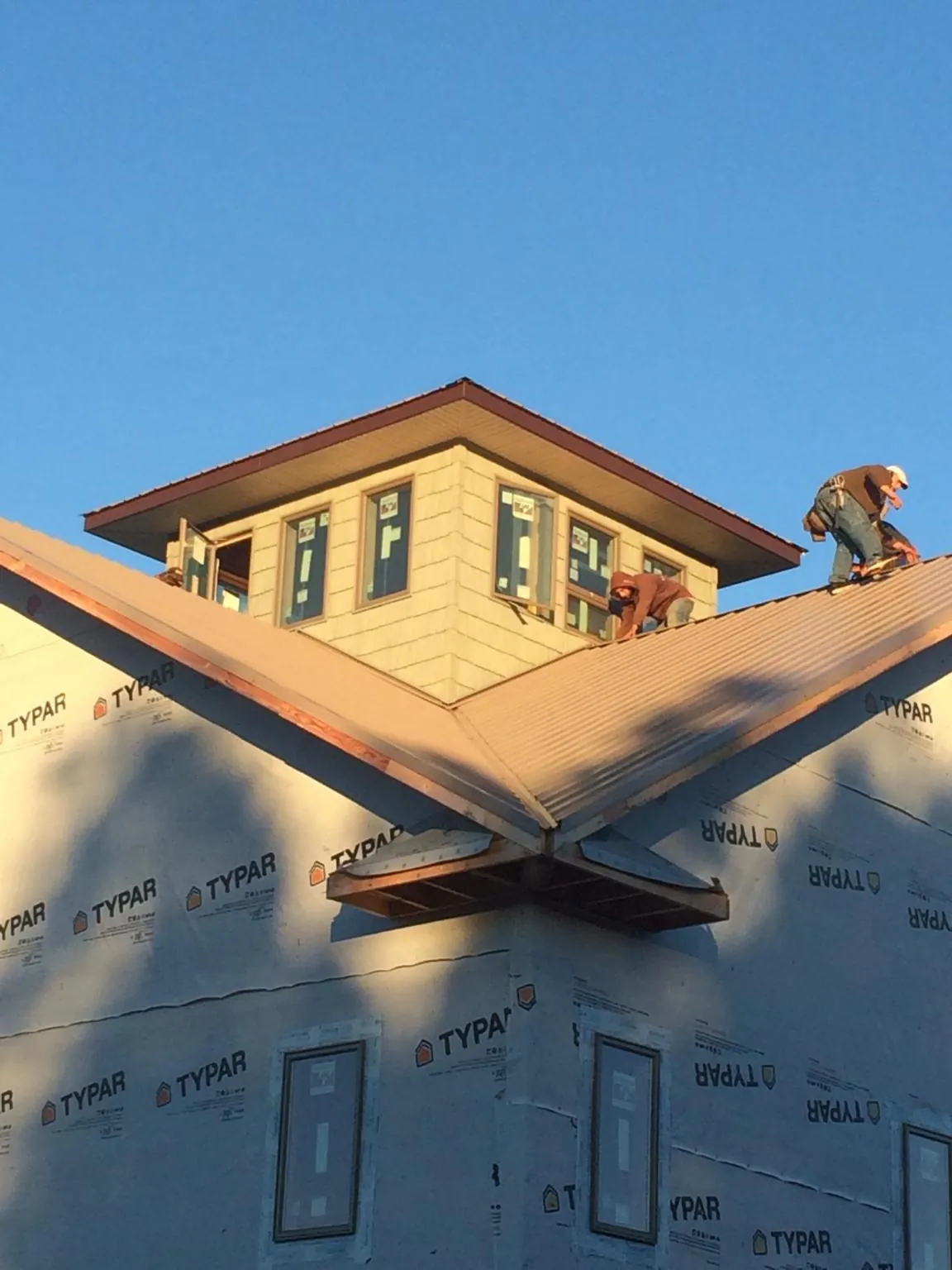 Roofers working around a rooftop cupola on a new metal roof at sunset — Roof Waterproofing in West Blocton by Roofing Brothers